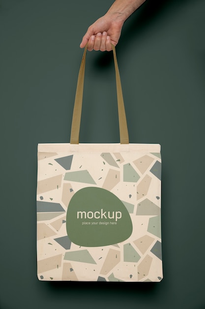Hand holding tote bag with green background | The Web Univers