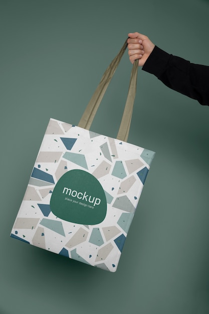 Hand holding tote bag with green background | The Web Univers