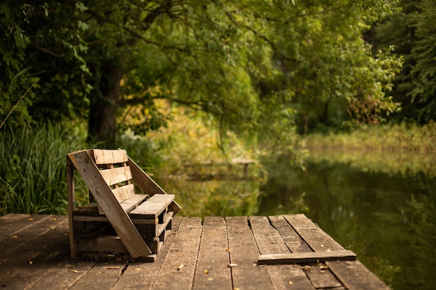 Wooden bench on the deck on the lake surrounded by greens | The Web Univers