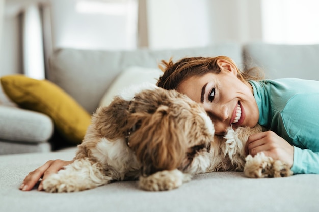 Affectionate woman cuddling her dog while relaxing at home | The Web Univers