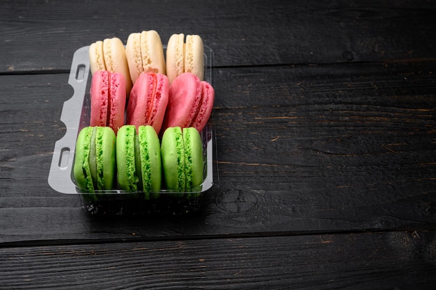 Macaroons. delicious french desserts set, in plastic pack, on black wooden table background, with copy space for text | The Web Univers